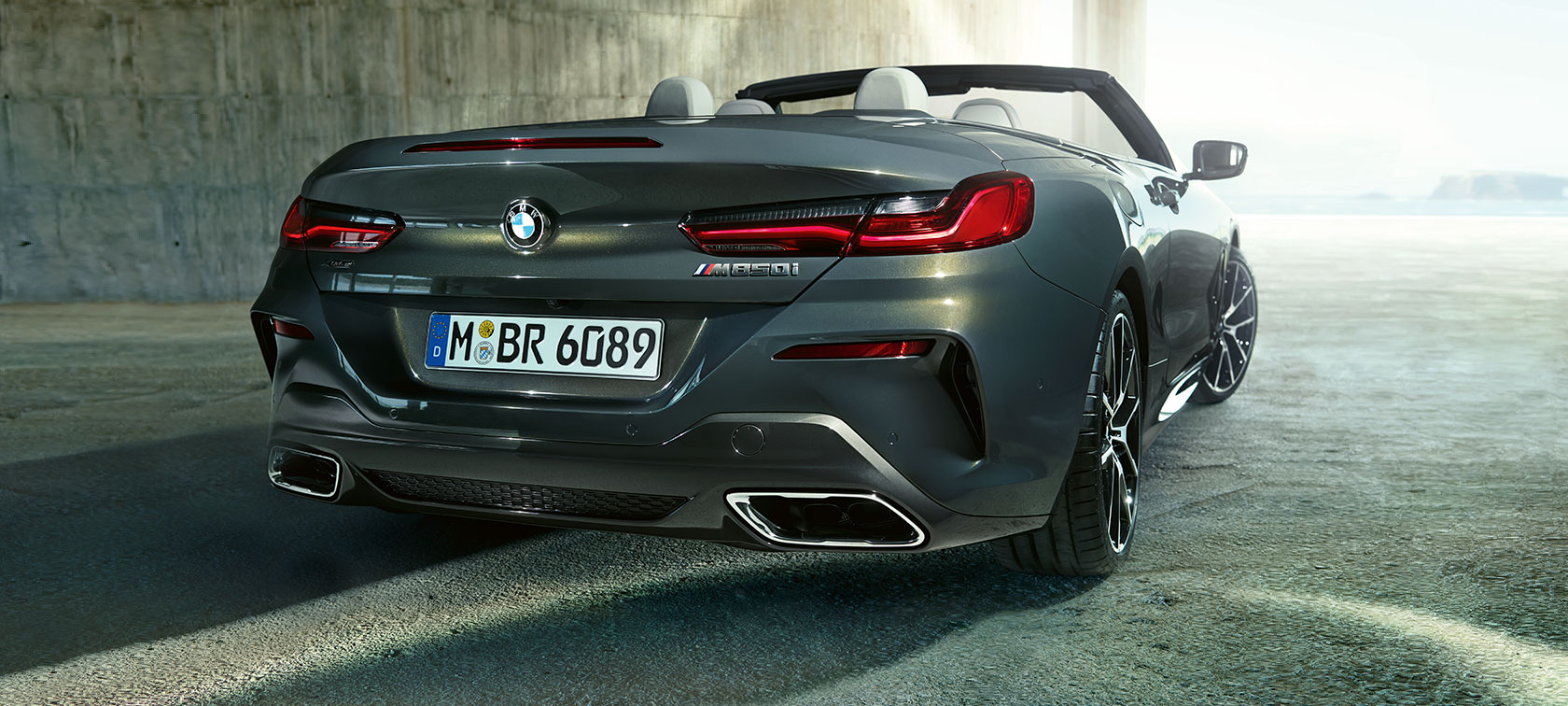 BMW M850i xDrive Dravit Grey metallic, three-quarter view rear.